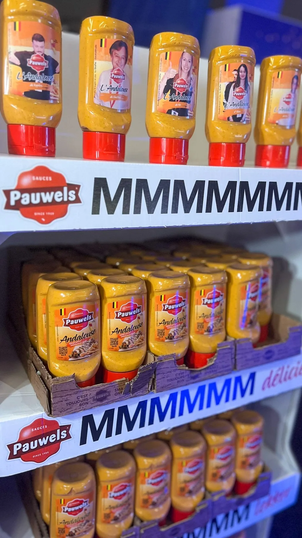 A shelf display with Pauwels bottles carrying visitors' photos above the regular bottles